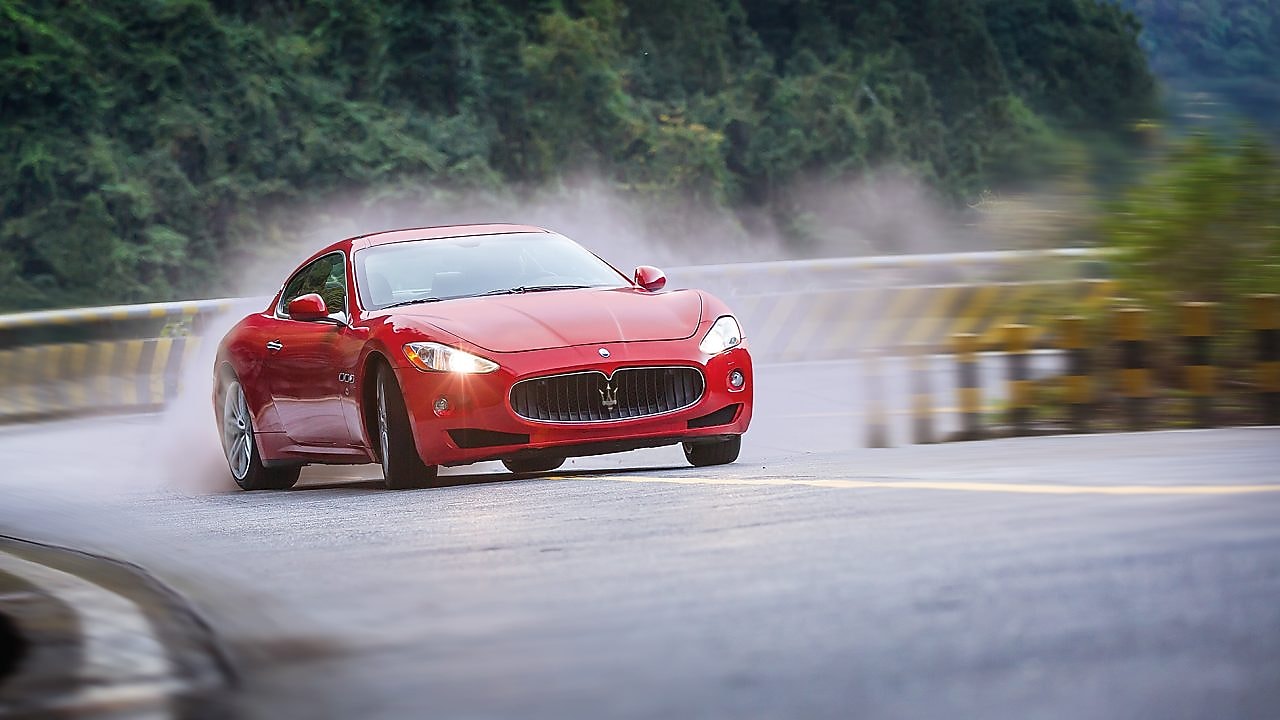 A red Maserati driving up a winding mountain road, representing the performance benefits of Shell Helix Ultra motor oil.