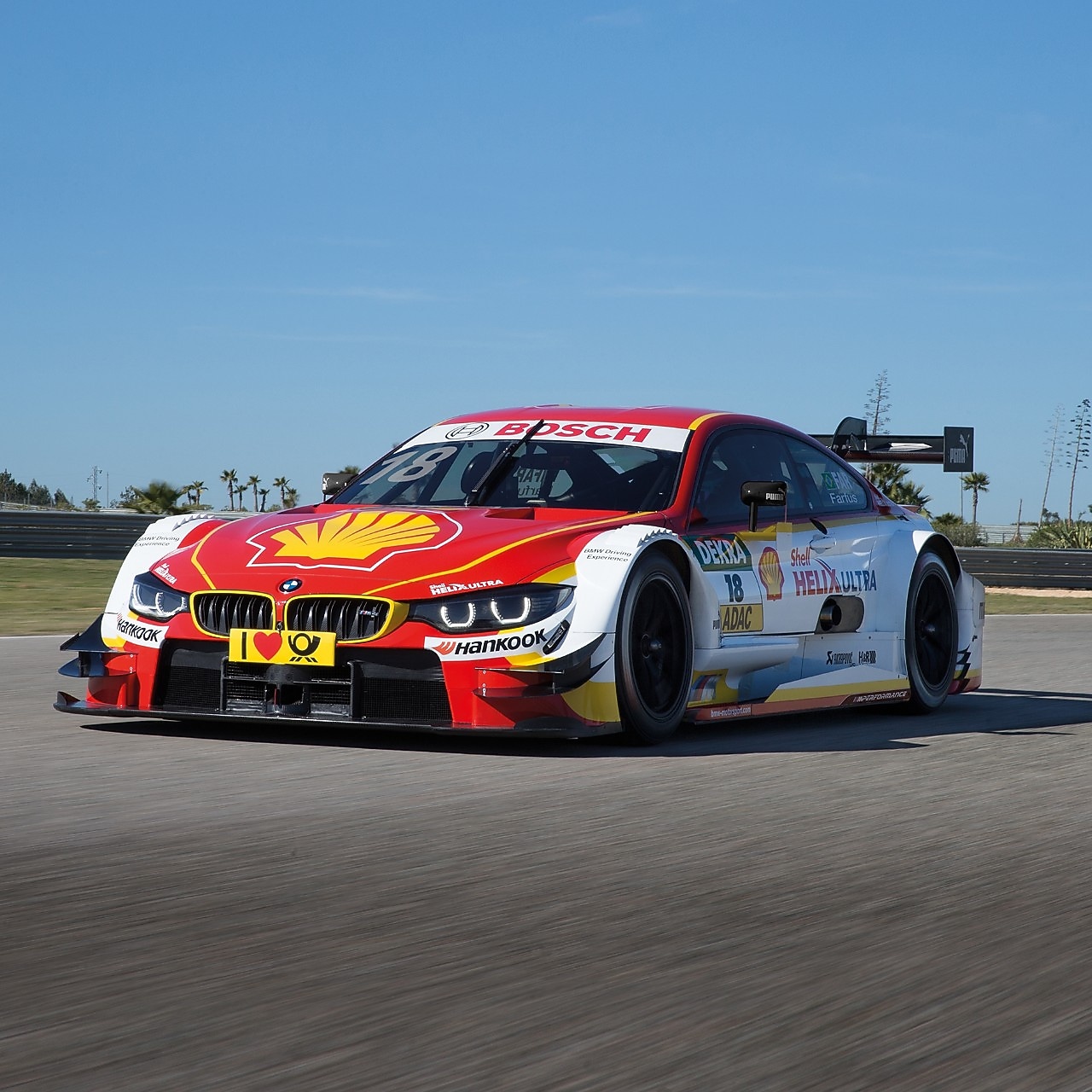 A BMW race car speeding on a track, demonstrating the power of Shell Helix lubricants.