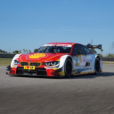 A BMW race car speeding on a track, demonstrating the power of Shell Helix lubricants.
