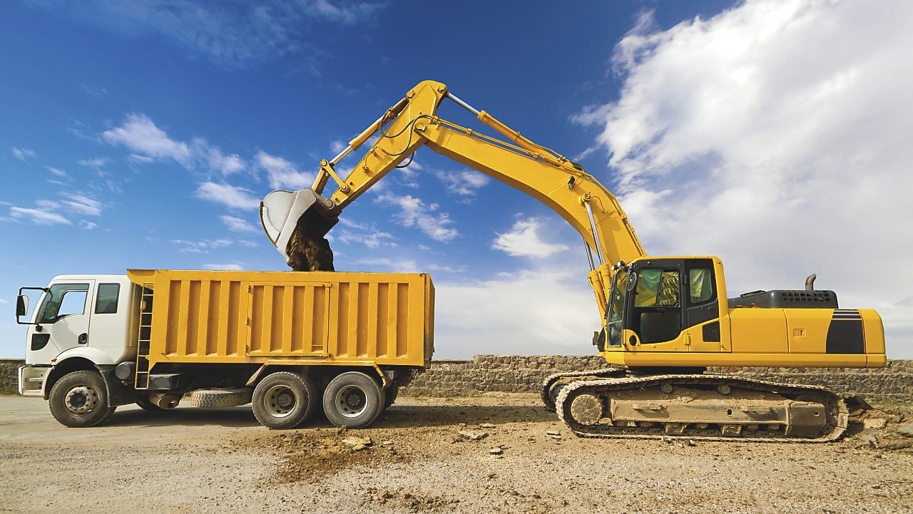 yellow excavator loading mud into a truck